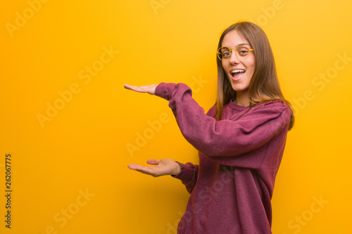 Young casual woman holding something very surprised and shocked