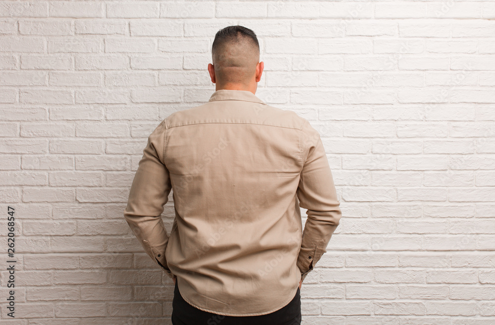 Obraz premium Young latin man from behind, looking back