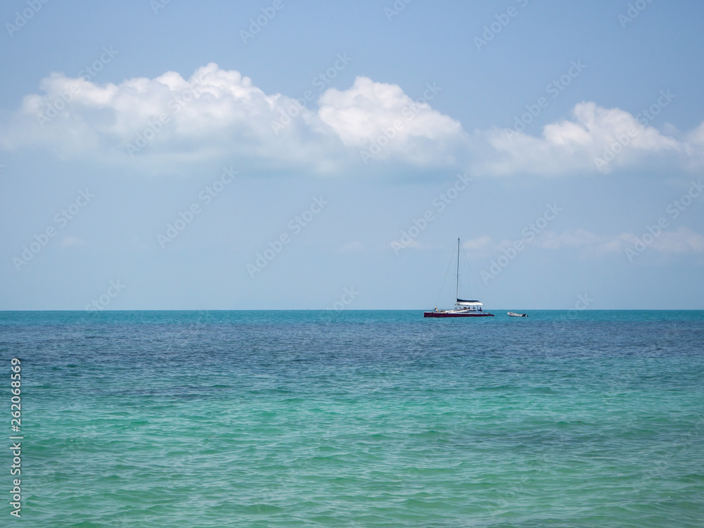 White yacht floating in the turquoise sea to the island with clouds. Koh Phangan. Thailand. White yacht floating in the turquoise sea to the island with clouds. Koh Phangan. Thailand.