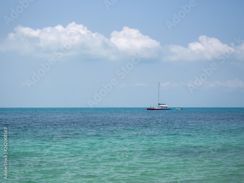 White yacht floating in the turquoise sea to the island with clouds. Koh Phangan. Thailand. 