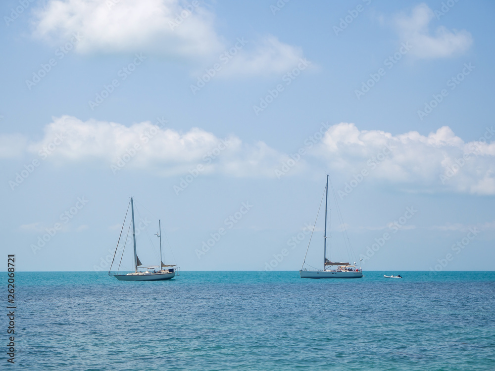 White yacht floating in the turquoise sea to the island with clouds. Koh Phangan. Thailand. White yacht floating in the turquoise sea to the island with clouds. Koh Phangan. Thailand.