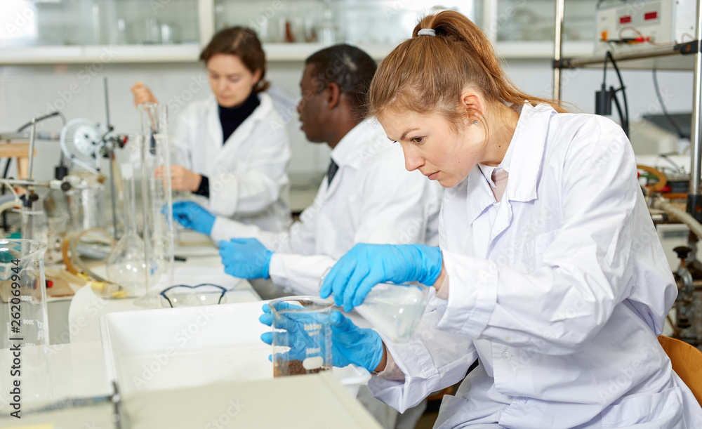 Fototapeta premium Young woman scientist working in research laboratory performing experiments