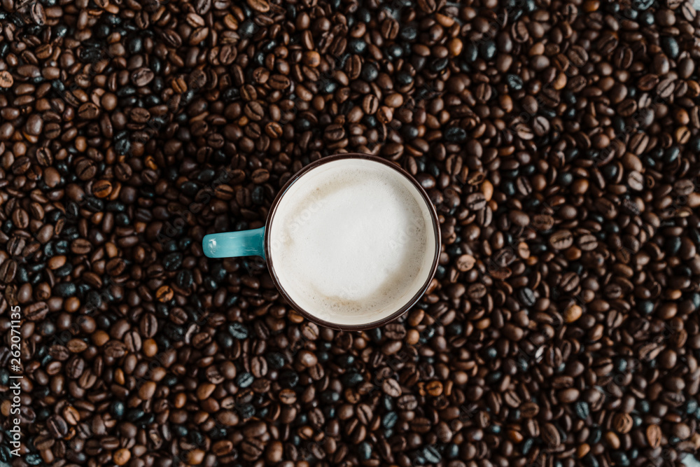 Cup of white coffee between coffee beans Cup of white coffee between coffee beans