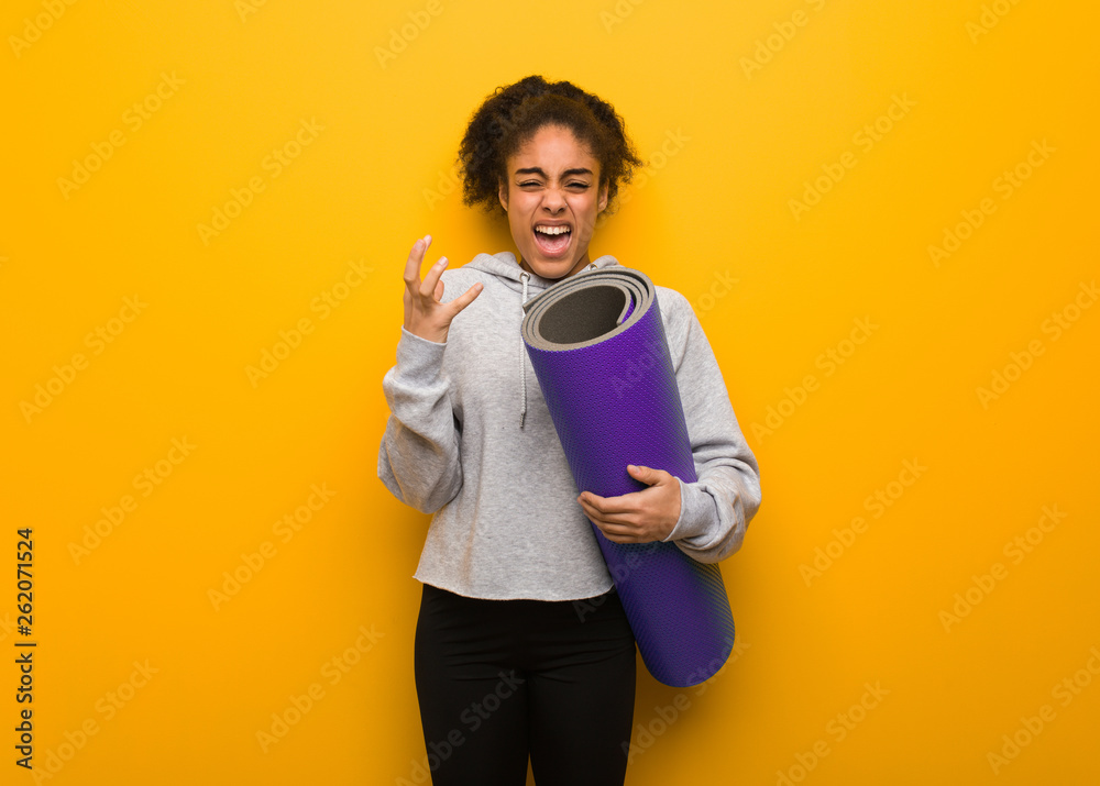 Young fitness black woman very scared and afraid. Holding a mat. Young fitness black woman very scared and afraid. Holding a mat.