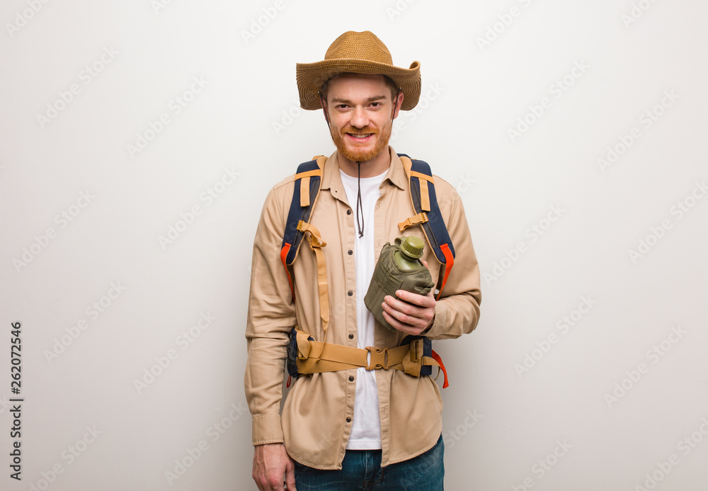 Young redhead explorer man cheerful with a big smile. He is holding a canteen. Young redhead explorer man cheerful with a big smile. He is holding a canteen.