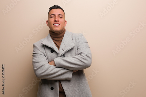Young latin business man smiling confident and crossing arms, looking up