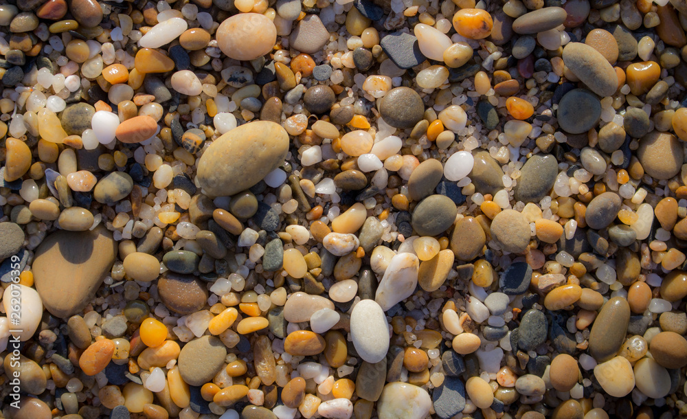 Colorful pebbles on beach. Pebbles closeup background. Small round stones in sunlight. Minerals concept. Sea shore background. Pebbles wallpaper. 