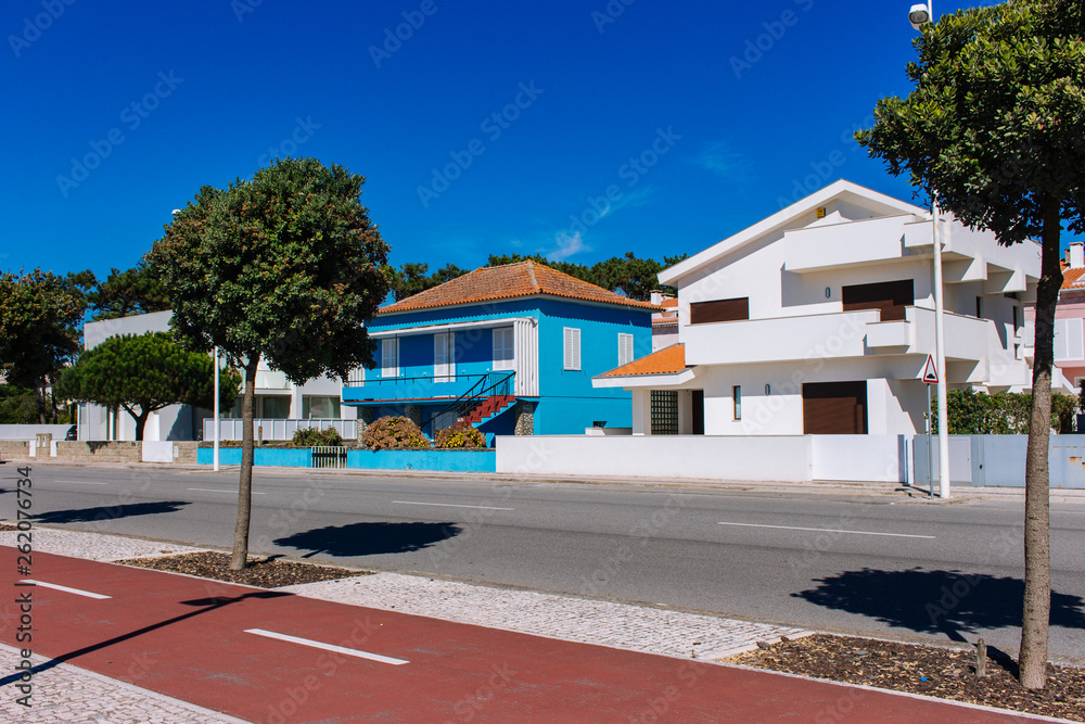 Esposende, Portugal - 10/03/2018: modern villas on sunny day. Traditional portuguese buildings with close shutters. Empty street on hot summer day. Daily siesta concept. Outdoor houses design. 