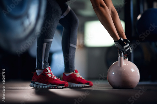 Unrecognizable athlete exercising with kettle bell on sport training in a gym.