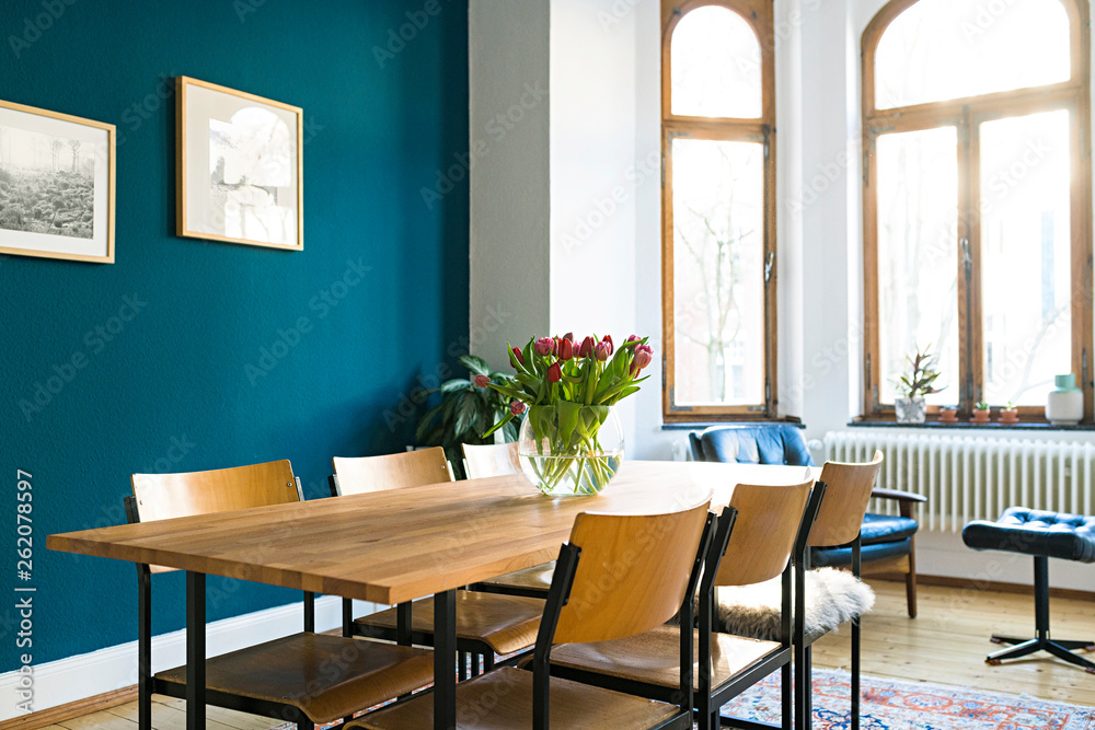 Wooden table and chairs with large window front in modern living room in stylish apartment