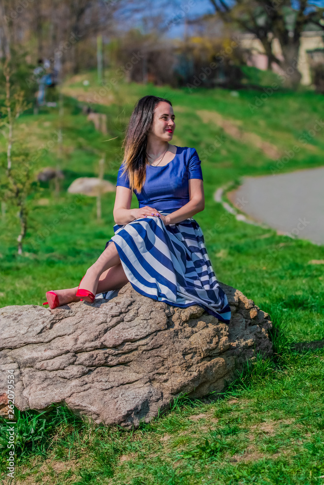 The young girl in dress with long skirt walks in the spring park. The beautiful nature in April. Sunny weather. Fashion. The young girl in dress with long skirt walks in the spring park. The beautiful nature in April. Sunny weather. Fashion.