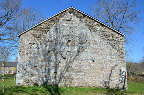 Tree shadow leans across the French Barn on a spring day