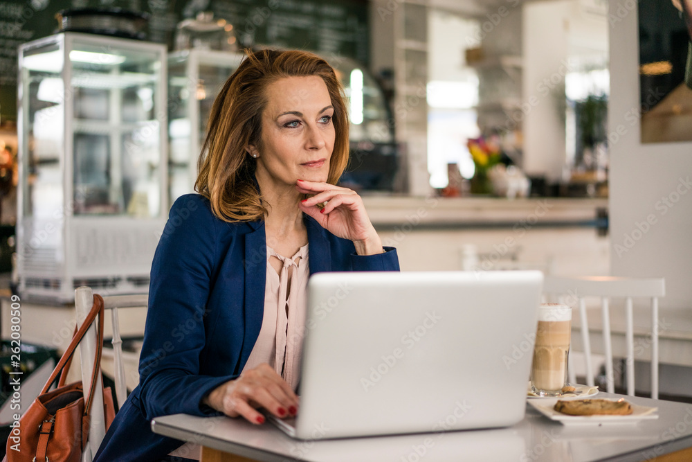 Businesswoman sitting in coffee shop, having lunch, working on laptop Businesswoman sitting in coffee shop, having lunch, working on laptop