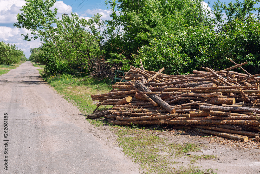 Big chaotic heap of pine wooden logs stocked near rural road at country village. Hardwood preparation and storage for future winter Big chaotic heap of pine wooden logs stocked near rural road at country village. Hardwood preparation and storage for future winter