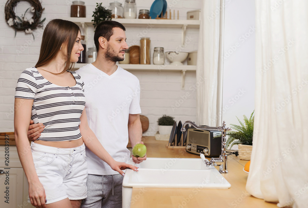 Young couple having nice time together at the kitchen on weekend and preparing food, washing dishes, making coffee in their new house Young couple having nice time together at the kitchen on weekend and preparing food, washing dishes, making coffee in their new house