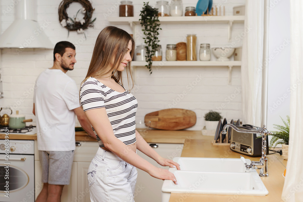 Young couple having nice time together at the kitchen on weekend and preparing food, washing dishes, making coffee in their new house Young couple having nice time together at the kitchen on weekend and preparing food, washing dishes, making coffee in their new house
