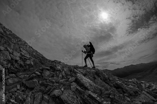 Girl with a back pack hikes up the mountain with polls, black and white, fisheye