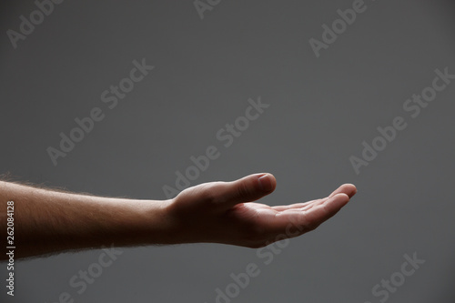 Photo of outstretched hand palm up on empty gray background.