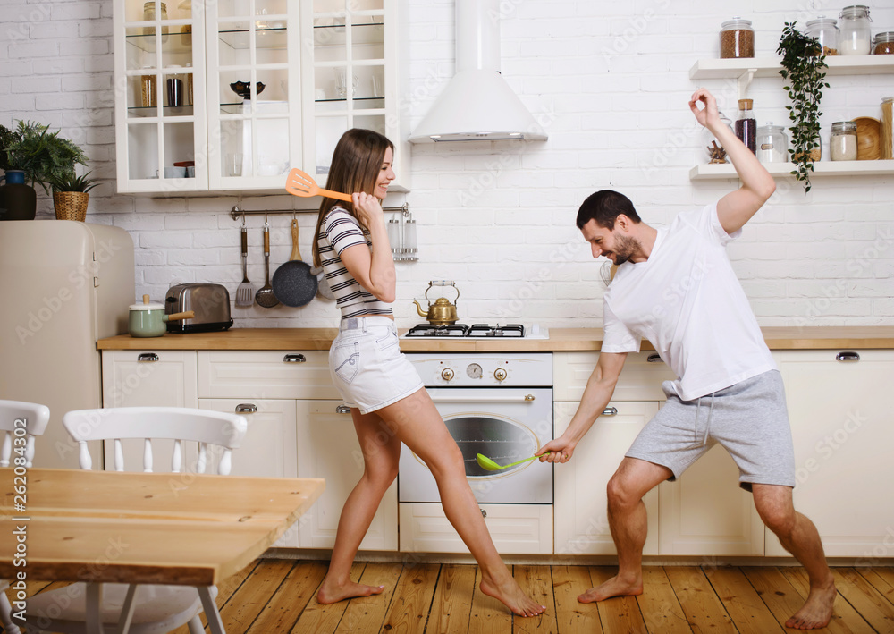 Funny couple fight with utensils tools while cooking at home together,  husband and wife having fun feeling playful holding kitchenware struggling  in the kitchen preparing healthy food Stock Photo | Adobe Stock