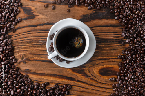 Coffee beans on wooden table with coffee cup. Top view