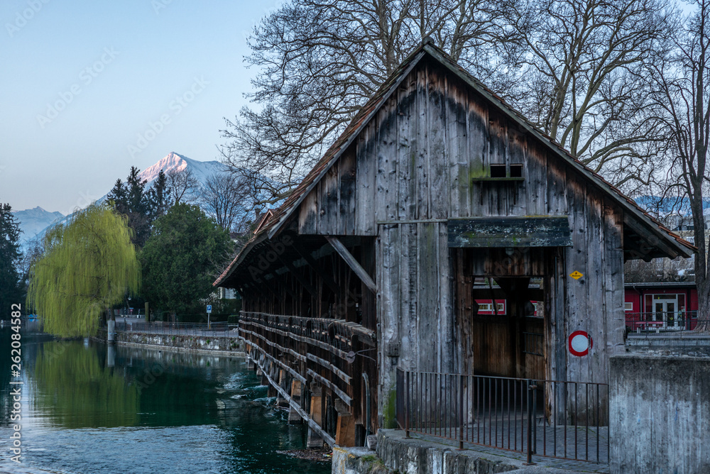 A wooden bridge crossing the river Aare in Thun with the Jungfrau and Eiger mountains in the background early in the morning - 1 A wooden bridge crossing the river Aare in Thun with the Jungfrau and Eiger mountains in the background early in the morning - 1