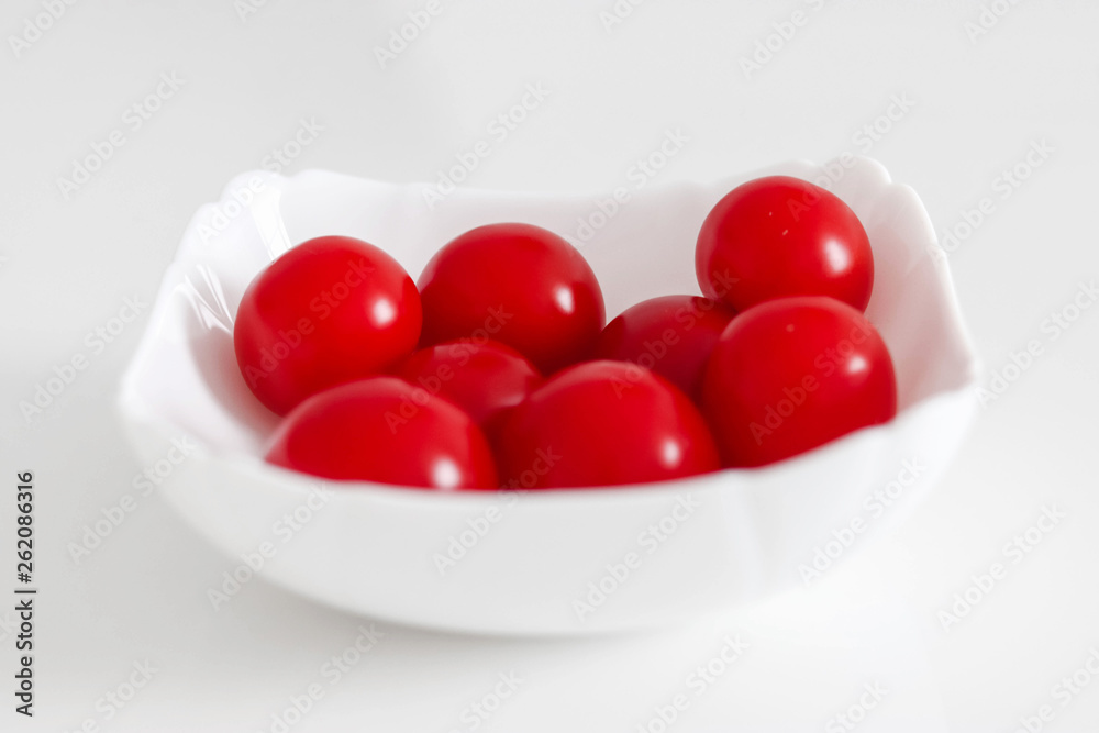 Fresh cherry tomatoes in a white plate, on a white background, White and Red Concept Fresh cherry tomatoes in a white plate, on a white background, White and Red Concept