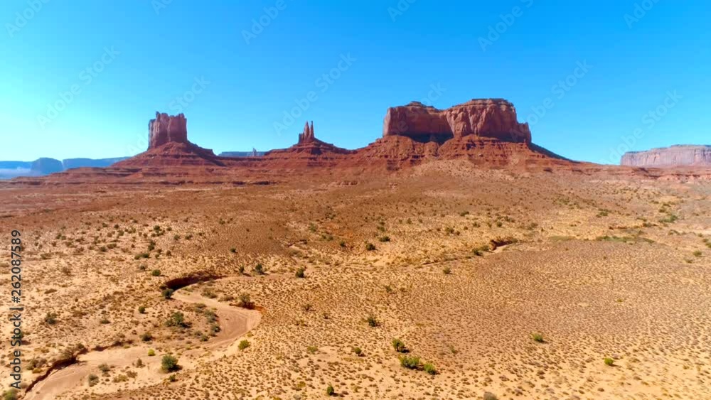 An iconic stretch of land with the sandstone buttes of the Monument Valley. 4K aerial shot of the red sandy landscape in summertime. An iconic stretch of land with the sandstone buttes of the Monument Valley. 4K aerial shot of the red sandy landscape in summertime.