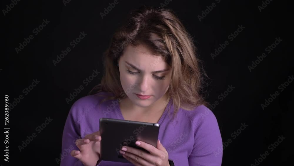 Portrait of woman working with tablet with perplexity on black background. Portrait of woman working with tablet with perplexity on black background.