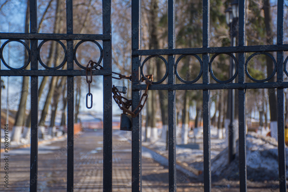 metal gate to the Park is closed with a lock and an iron chain metal gate to the Park is closed with a lock and an iron chain