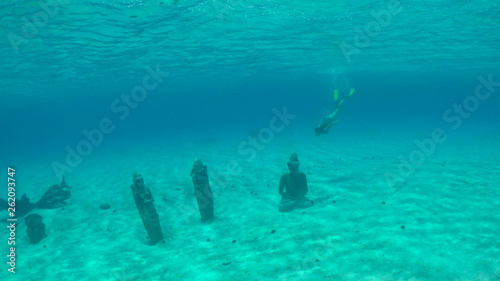 UNDERWATER: Woman on vacation diving and exploring ruins of old buddha statues.