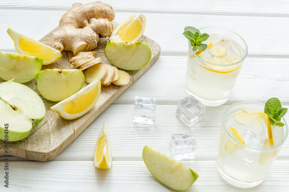 summer cocktails for freshness with ice, ginger, mint, apple and lemon on white wooden background summer cocktails for freshness with ice, ginger, mint, apple and lemon on white wooden background