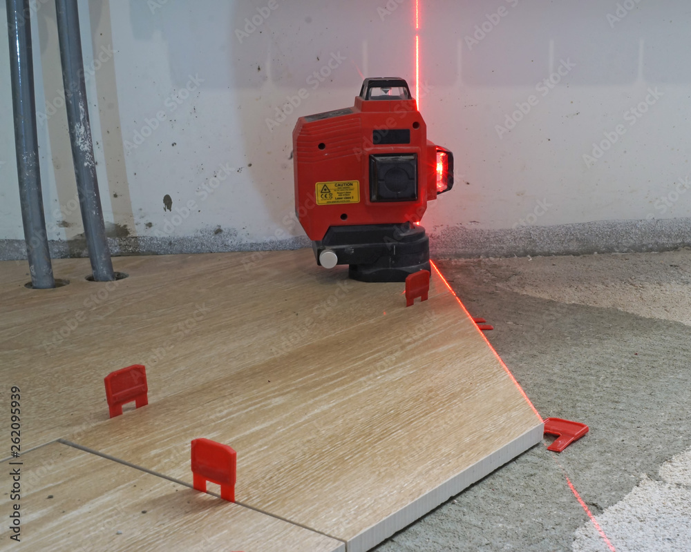 Professional tile work. Using laser level measuring tool for laying ceramic  floor tiles Stock Photo | Adobe Stock