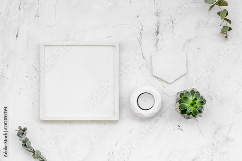 modern design of work desk with plant, candle on white marble background top view copy space