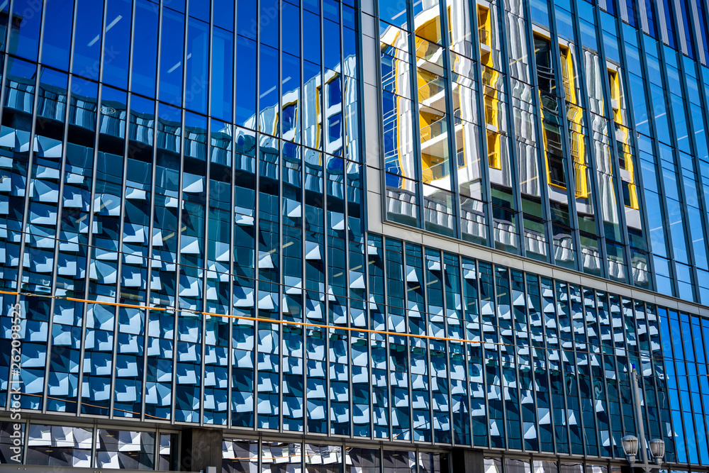 Fototapeta premium High-rise modern building with glass exterior reflects the opposite building