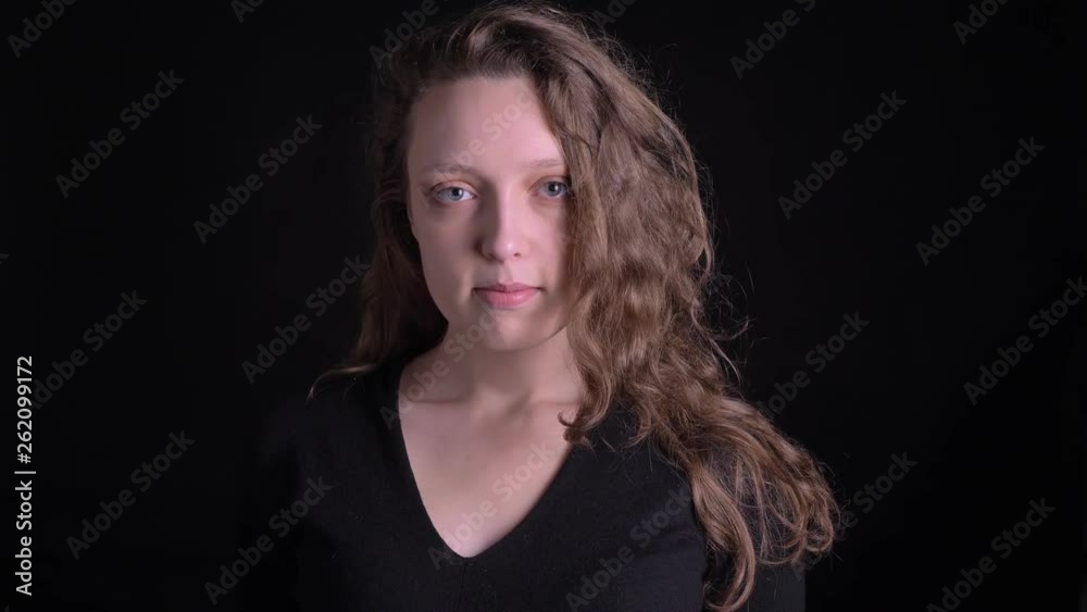 Portrait of young curly-haired girl watching awkwardly into camera on black background. Portrait of young curly-haired girl watching awkwardly into camera on black background.