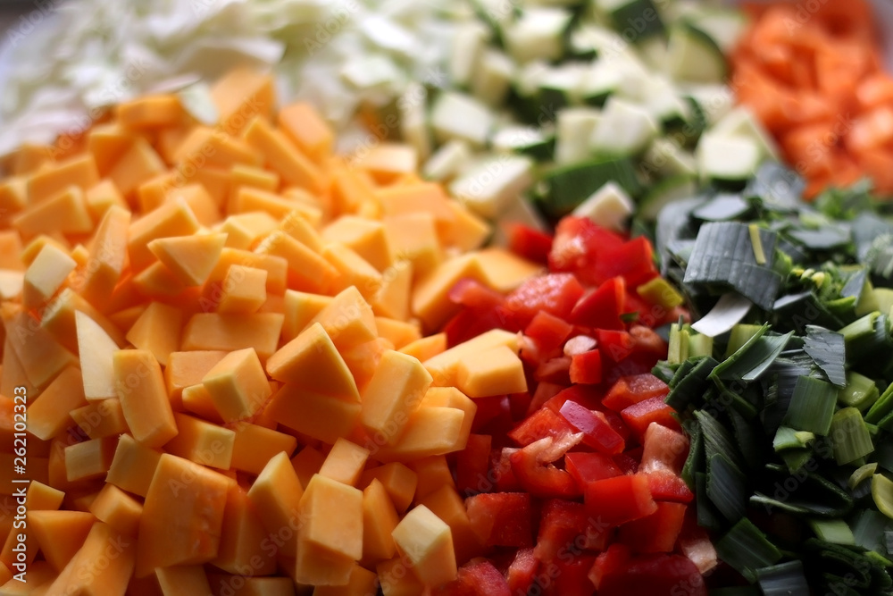 Various chopped vegetables: butternut squash, cabbage, red pepper, courgette, leek and carrot. Top view, selective focus.