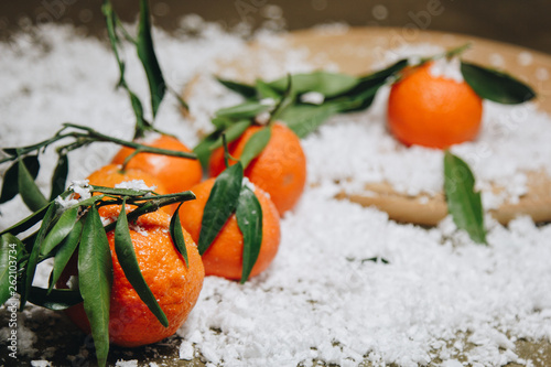 Mandarin citrus fruit with leaves on a wooden kitchen table on a blurred background. healthy food. raw food Artificial white snow. New Year. Christmas