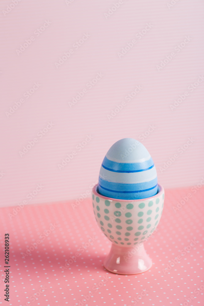 Closeup colorful painted Easter egg in vibrant modern egg stand on pastel pink background. Closeup colorful painted Easter egg in vibrant modern egg stand on pastel pink background.