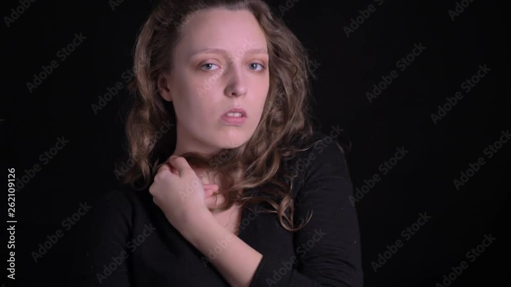 Portrait of young curly-haired girl posing fashionably into camera and adjusting hair on black background. Portrait of young curly-haired girl posing fashionably into camera and adjusting hair on black background.