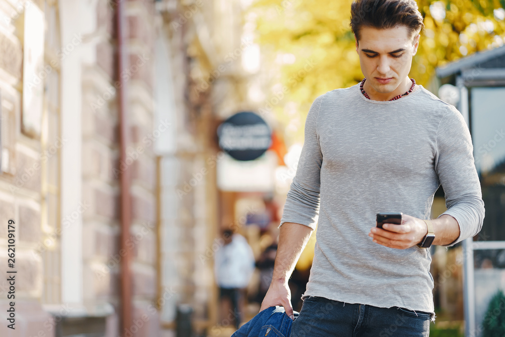 stylish man using his phone while walking through the city by himself stylish man using his phone while walking through the city by himself