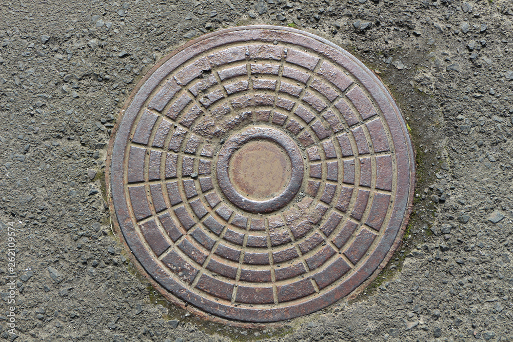 cast iron manhole on asphalt background