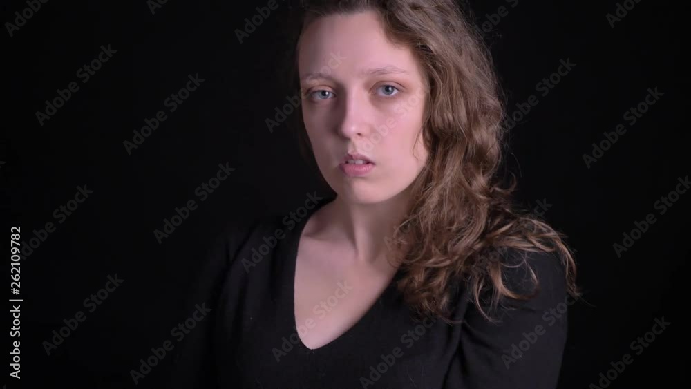 Portrait of young curly-haired girl posing fashionably into camera and seriously on black background. Portrait of young curly-haired girl posing fashionably into camera and seriously on black background.