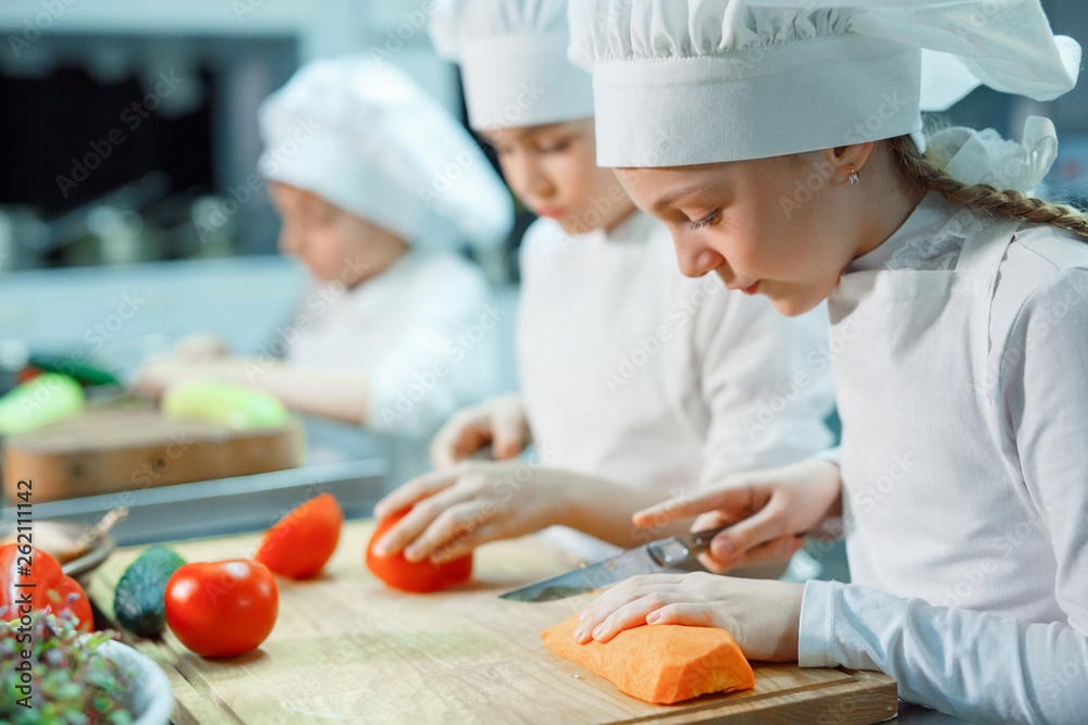 Children grind vegetables in the kitchen. Children grind vegetables in the kitchen.