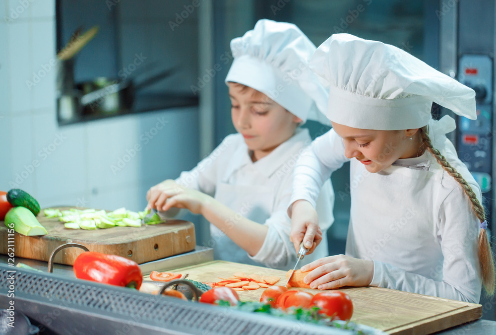 Children grind vegetables in the kitchen.