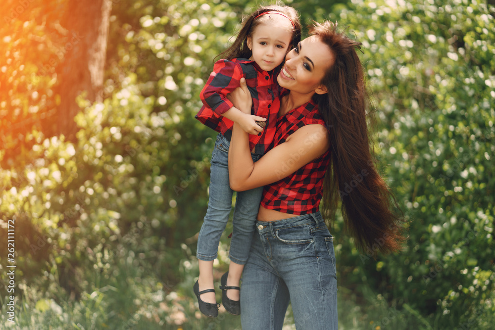 Young and very beautiful slim mum with long hair walking in a sunny summer park with her little beauties daughter Young and very beautiful slim mum with long hair walking in a sunny summer park with her little beauties daughter