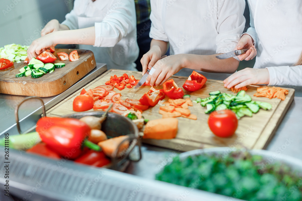 Children grind vegetables in the kitchen.