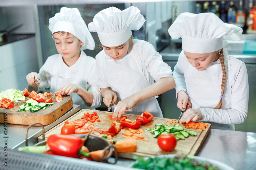Children grind vegetables in the kitchen. Children grind vegetables in the kitchen.