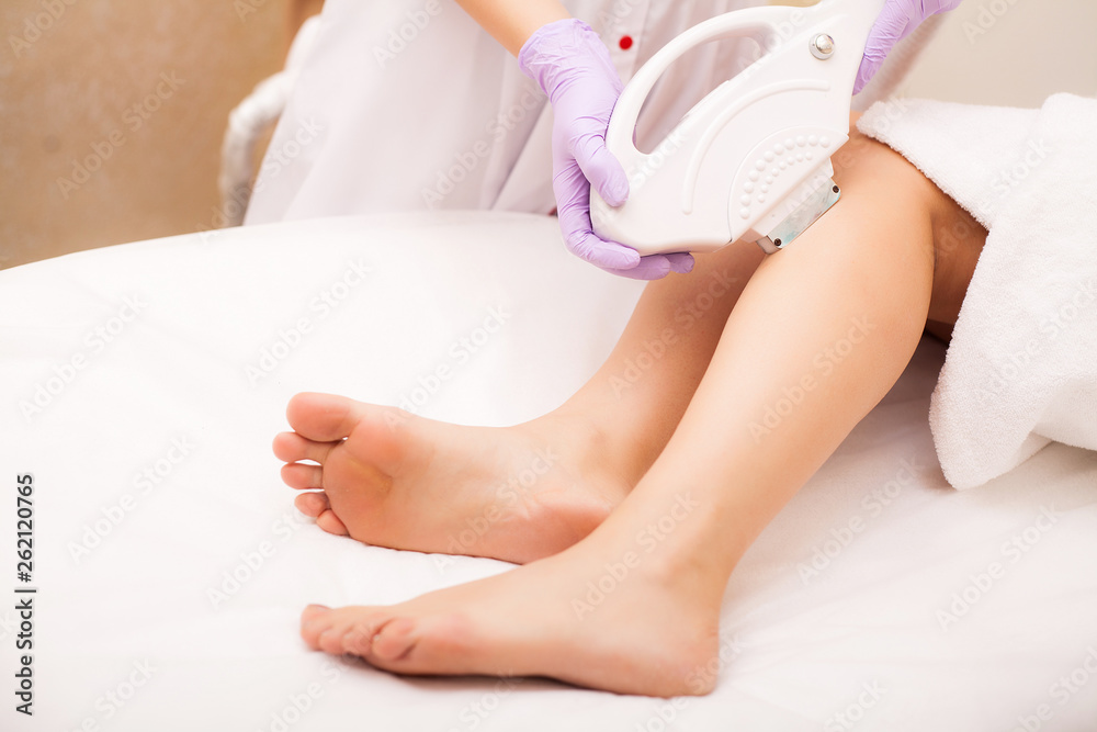 Obraz premium Skin Care. Hair removal on the legs, laser procedure at clinic. Beautician removes hair on beautiful female legs using a laser