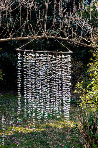 Sculpture of 1000 origami paper cranes hung from an overhead branch in a garden, vertical aspect photo