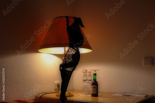 Dieses einzigartige Bild zeigt einen schwarzen BH über einer Lampe und davor eine kleine Flasche Rotwein. Dieses Bild wurde in einem Hotel in Bayern Deutschland aufgenommen